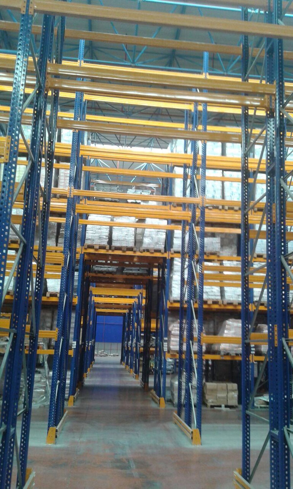 Paletli yüklerle dolu ikinci el ağır yük rafı hatları ve aralarındaki forklift koridoru