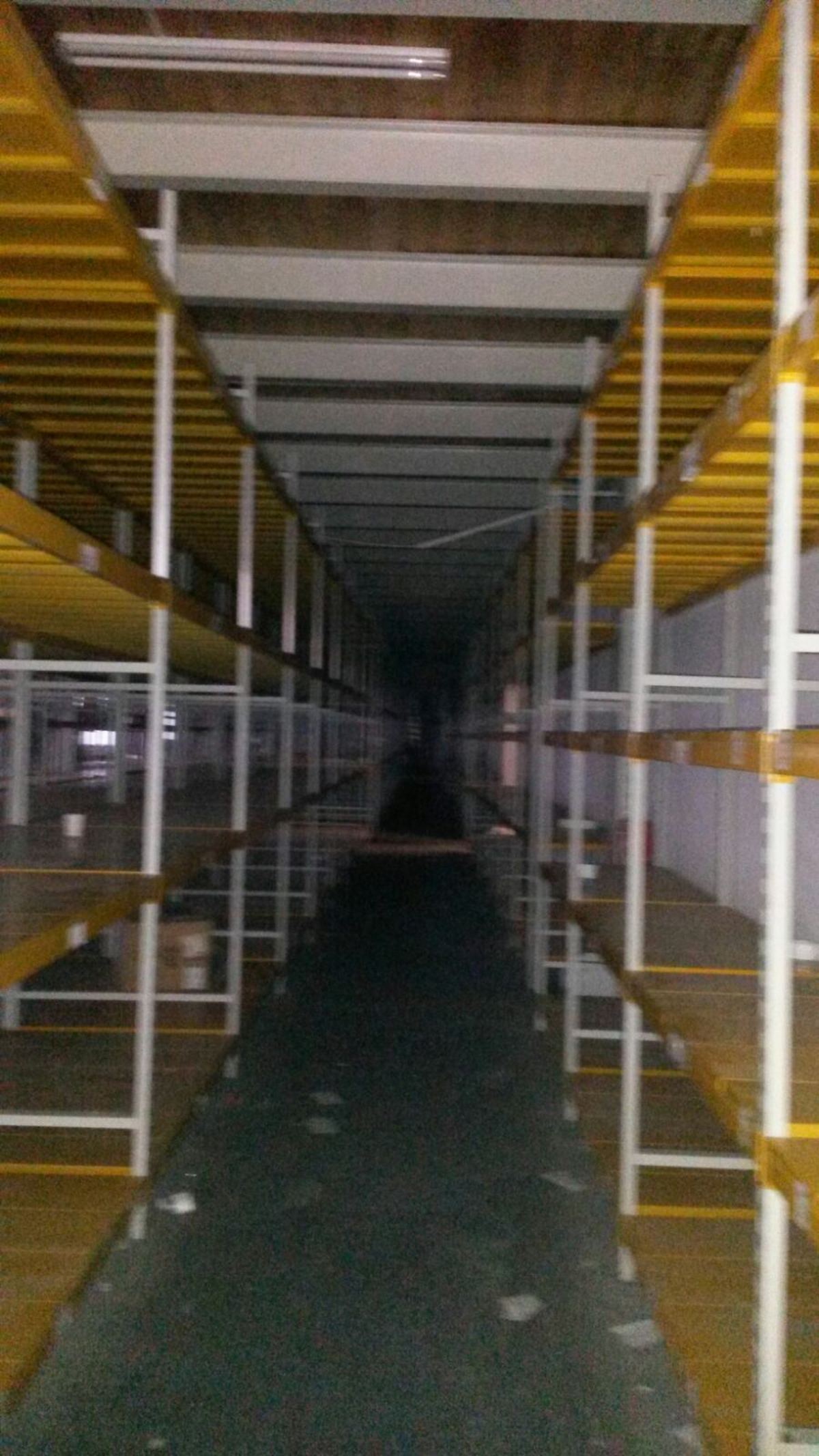 Dar bir koridor boyunca uzanan, sık gözlü ikinci el hafif yük rafı hattı