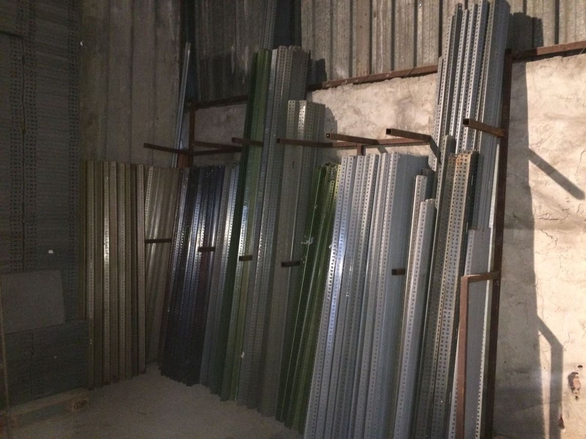 Depo duvarına dayanmış, renkleri ve boyları birbirinden farklı ikinci el raf dikmeleri